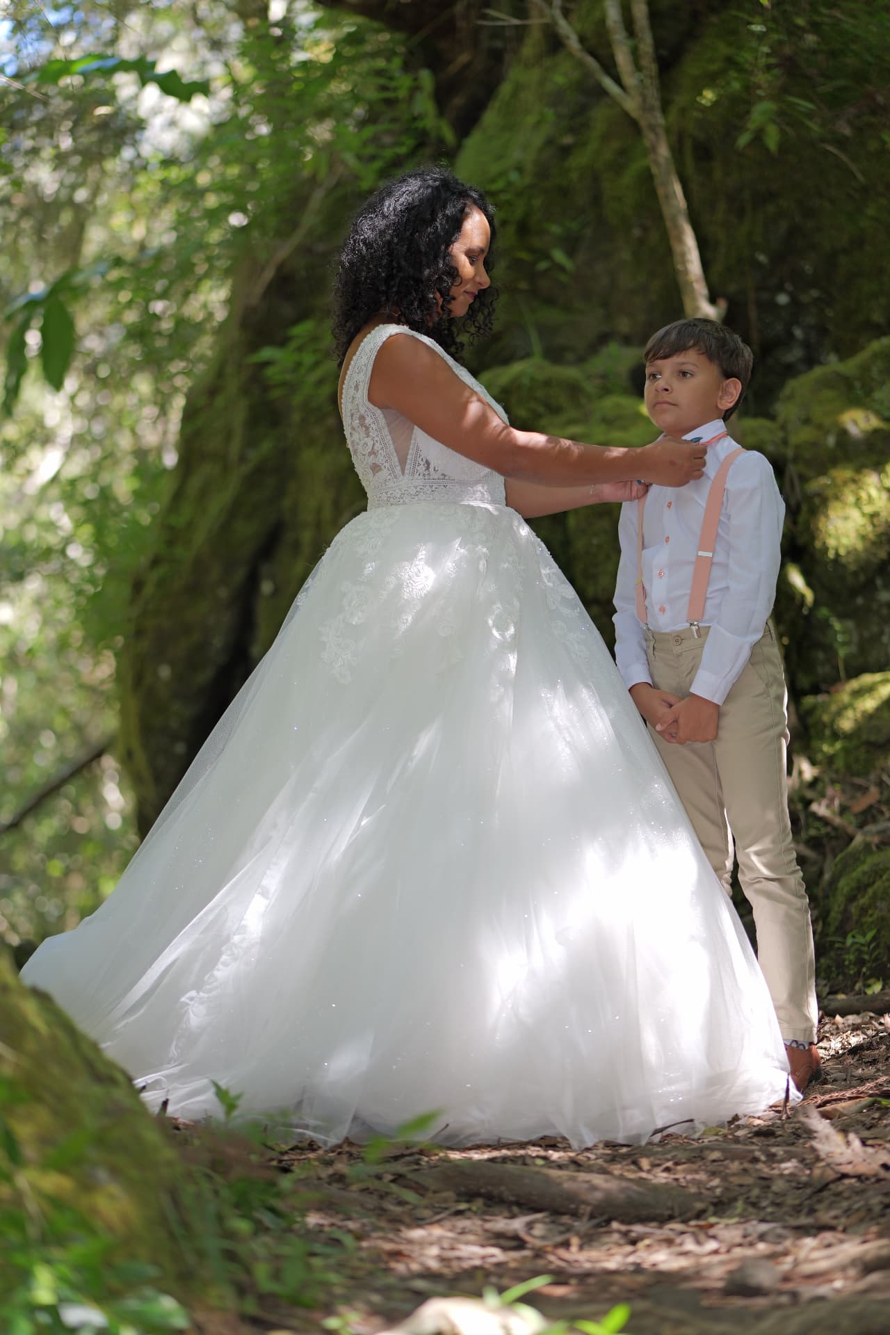 La mariée ajuste la tenue d'un jeune garçon dans la forêt